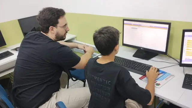 Monitor ajuda um jovem a montar blocos de código no Scratch